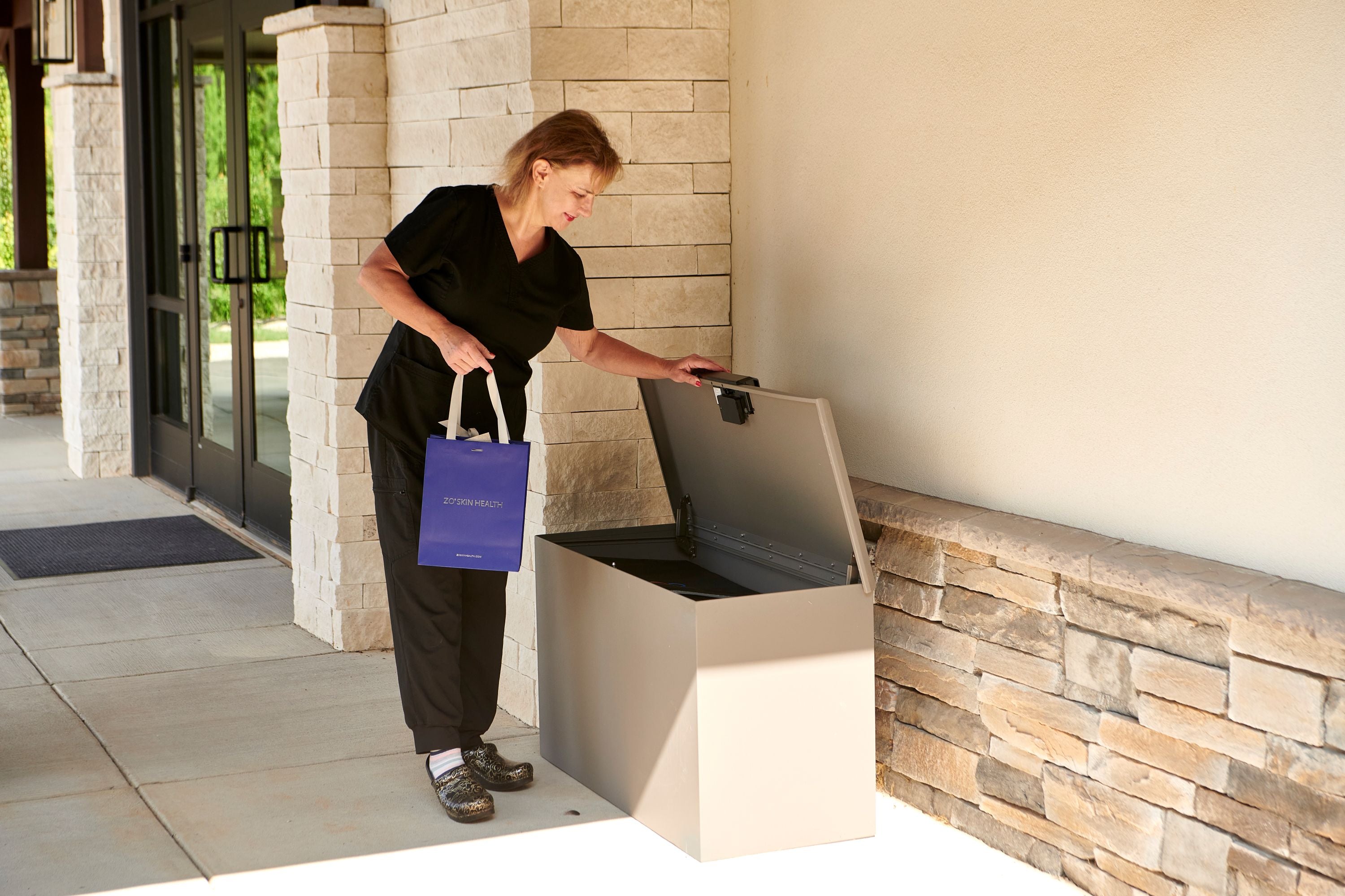 Person using a smart LOXX BOXX  with a blue bag in front of office.